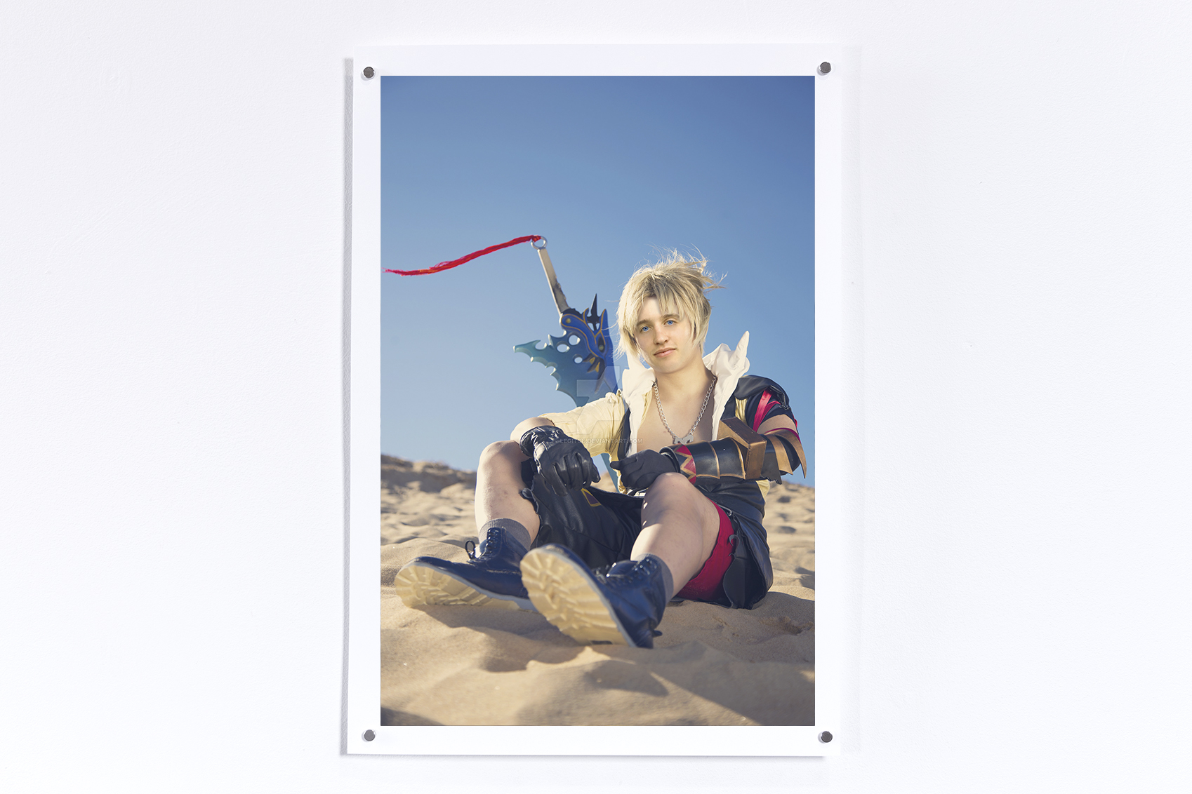 Print hung on a white wall of Tidus from Final Fantasy 10 seated on a beach with Jesse's face superimposed on the character